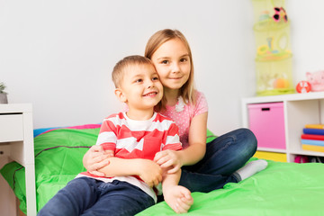 Poster - childhood, leisure and family concept - happy little kids hugging at home