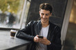 © Goran - Smiling young man text messaging on mobile phone