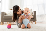 family and motherhood concept - happy smiling young asian mother with little baby at home