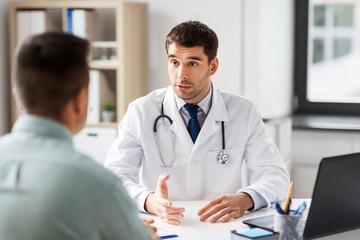 Poster - medicine, healthcare and people concept - doctor talking to male patient at medical office in hospital