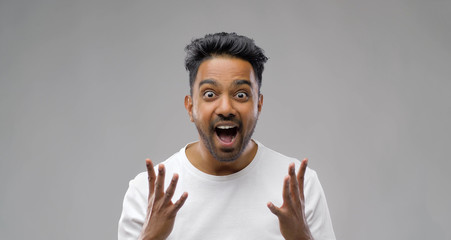 success, emotion and expression concept - happy young indian man celebrating victory over grey background