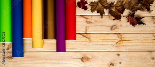 Fotomural Panned colorful vinyl rolls on wooden background placed in a row with autumn lea