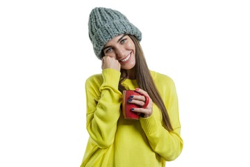 Wall Mural - Portrait of smiling winter young woman in knitted hat, yellow sweater with cup of hot drink, isolated on white