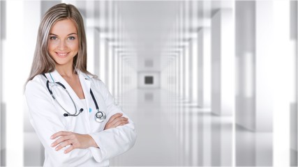 Wall Mural - Attractive young female doctor with blurred hospital interior on