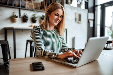 smiling woman typing on laptop indoors.