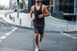 © MARIIA - Motion in his body. Part of young man in sportswear jogging against industrial city view
