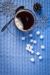 Wall Mural - a Cup of Christmas hot coffee with marshmallows and snowflakes on a blue textile background