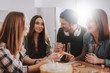 © Yakobchuk Olena - Bearded man in hat holding bottle of beer while sitting at the table with three charming girls. He is looking at brunette lady and smiling