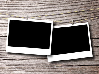 Two blank rectangular instant photo frames on brown wooden boards background