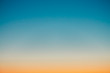 canvas print picture - Predawn clear sky with orange horizon and blue atmosphere. Smooth orange blue gradient of dawn sky. Background of beginning of day. Heaven at early morning with copy space. Sunset, sunrise backdrop.