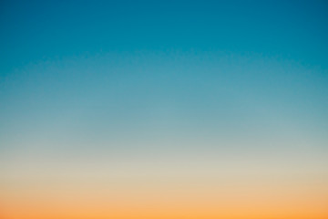 predawn clear sky with orange horizon and blue atmosphere. smooth orange blue gradient of dawn sky. 