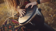 Beautiful Young Hippie Woman With Dreadlocks Playing On Djembe. Funky Woman Drumming In Nature On An Ethnic Drum At Sunset Or Sunrise