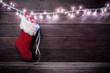 Santa stocking with gift boxes on wooden background.