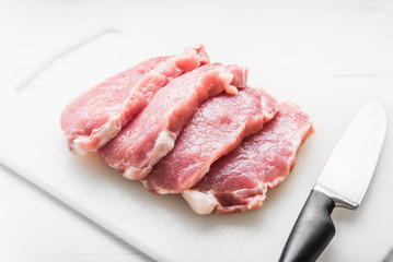 Sliced pork on white board and knife on white table