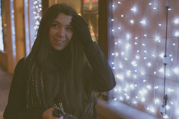 Girl Eastern looks, walking through the city at night, in the winter. Woman in winter jacket with scarf. Street style clothing