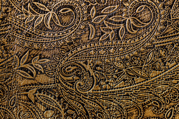 Texture of golden brown genuine leather close-up, with embossed floral trend pattern, wallpaper or banner design