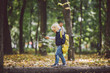 The theme children outdoor activities. Funny little baby Caucasian blond girl walks through forest overcoming obstacles, tree fell, log. Baby hiking big funny backpack in autumn forest park