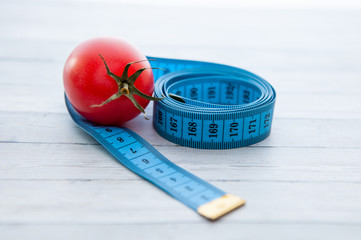 Measuring tape and juicy tomato, the concept of healthy nutrition and weight loss