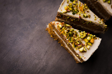 Raw vegan pistachio carrot cake with cashew cream layers from above on concrete table. Dark food photography styling concept. Horizontal