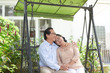 © DragonImages - Senior Asian couple in love resting on swing in backyard
