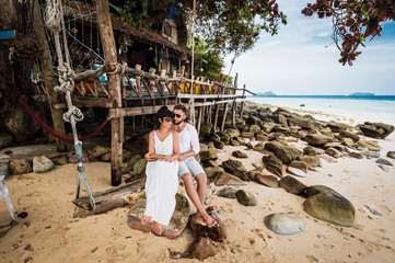 Couple in love on a swing by the sea. Couple in love on an island off the coast. Honeymoon. Couple by the sea. A guy and a girl travel to beautiful places. Honeymoon trip. Relax on the island