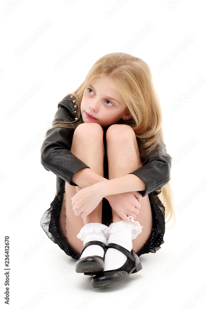 A little girl is sitting on the floor, hugging her knees. Stock Photo ...