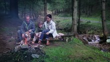 Mother, Fgather And Son With Their Beagle Dog Grill The Marshmallows In The Deep Forest Near The Cold Creek.Family Weekend Picnic Concept HD Footage.