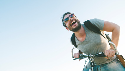 Active sport man with excited face expression exploring and traveling by mountain bike on the road. Vintage film filter style image.