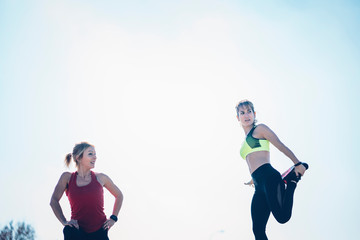 Wall Mural - Two beautiful women perform outdoor exercise in park.