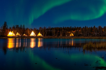 light up tipi (indian tent) with water reflection during aurora borealis (northern light) at yellow 