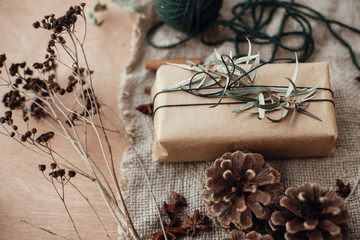 Wall Mural - Stylish rustic christmas gift box with green branch and fir branches, anise, pine cones, cinnamon on rustic wooden background. Simple eco friendly present wrapping. Atmospheric mood