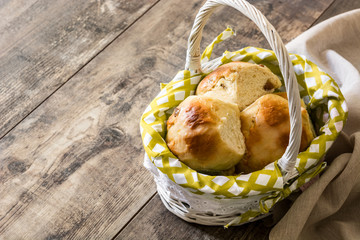 Traditional Easter hot cross buns in a basket on wooden table. Copyspace