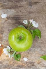 Wall Mural - Fresh sweet juicy green apples with flowers on a wooden background