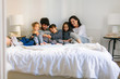 © BONNINSTUDIO/Stocksy - Portrait of happy family wearing pajama resting on bed.