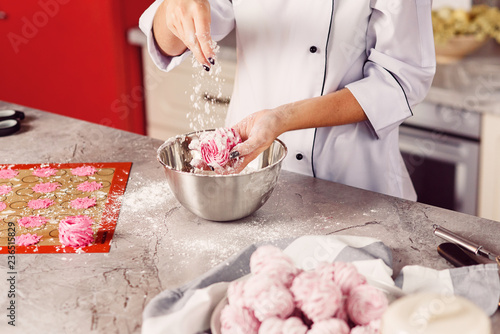 Fotografie, Obraz The chef sprinkles homemade marshmallows with sugar powder