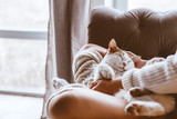 Fototapeta Koty - Girl with cat relaxing on a sofa