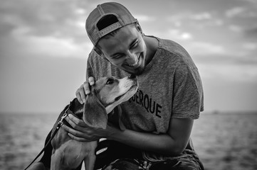 Black and white photo of a guy with a dog on the beach