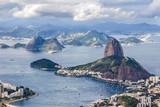 Fototapeta Nowy Jork - Views from Christ The Redeem mountain over Sugar Loaf, Rio do Janeiro city, suburbs and favelas, amazing views over the bays, islands, beach and the city skyline from the top on a cloudy day, Brazil
