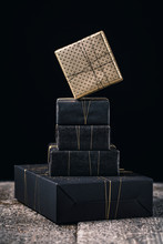 Gift Wrapped In Gold Hanging Over Black Gifts
