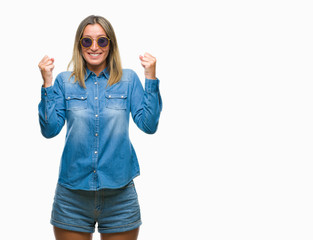 Young beautiful woman wearing sunglasses over isolated background celebrating surprised and amazed for success with arms raised and open eyes. Winner concept.