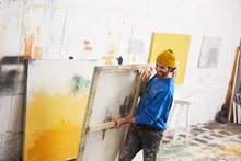 Painter Smiling While Carrying Painting In Studio