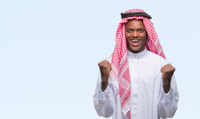 Young arabic african man wearing traditional keffiyeh over isolated background celebrating surprised and amazed for success with arms raised and open eyes. Winner concept.