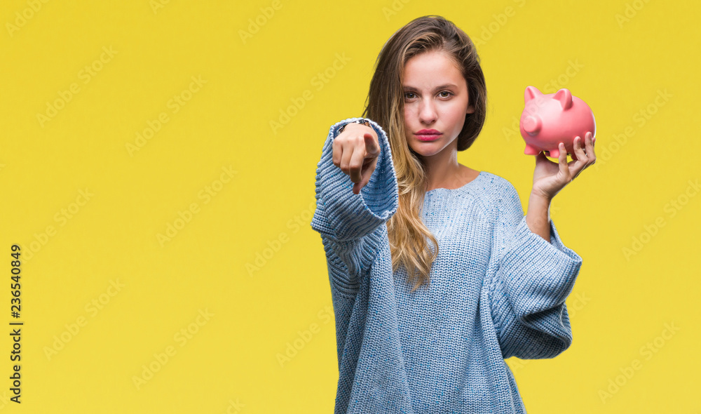 Young beautiful blonde woman holding piggy bank over isolated ...