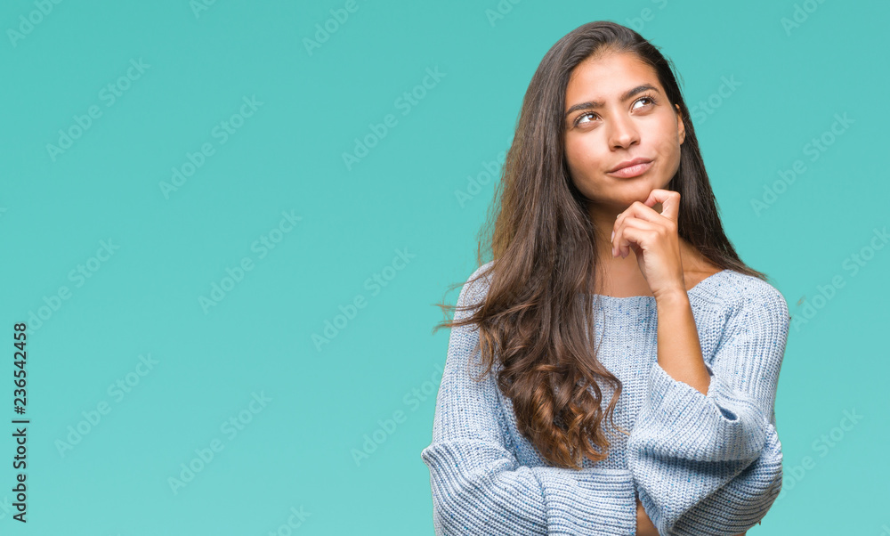Young beautiful arab woman wearing winter sweater over isolated background with hand on chin thinking about question, pensive expression. Smiling with thoughtful face. Doubt concept. - obrazy, fototapety, plakaty 