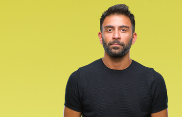 Adult hispanic man over isolated background with serious expression on face. Simple and natural looking at the camera.