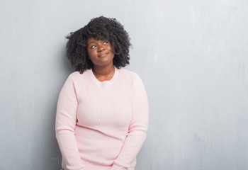 Poster - Young african american plus size woman over grey grunge wall wearing winter sweater smiling looking side and staring away thinking.