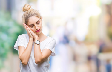 Sticker - Young beautiful blonde woman wearing white t-shirt over isolated background sleeping tired dreaming and posing with hands together while smiling with closed eyes.