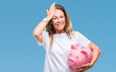 Middle age hispanic woman saving money using piggy bank over isolated background stressed with hand on head, shocked with shame and surprise face, angry and frustrated. Fear and upset for mistake.