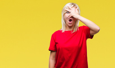 Poster - Young beautiful blonde woman wearing red t-shirt over isolated background peeking in shock covering face and eyes with hand, looking through fingers with embarrassed expression.