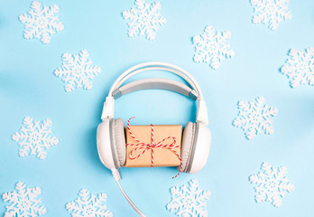 Wall Mural - White headphones with  new year or christmas gift box and decorative snowflakes on a blue background.